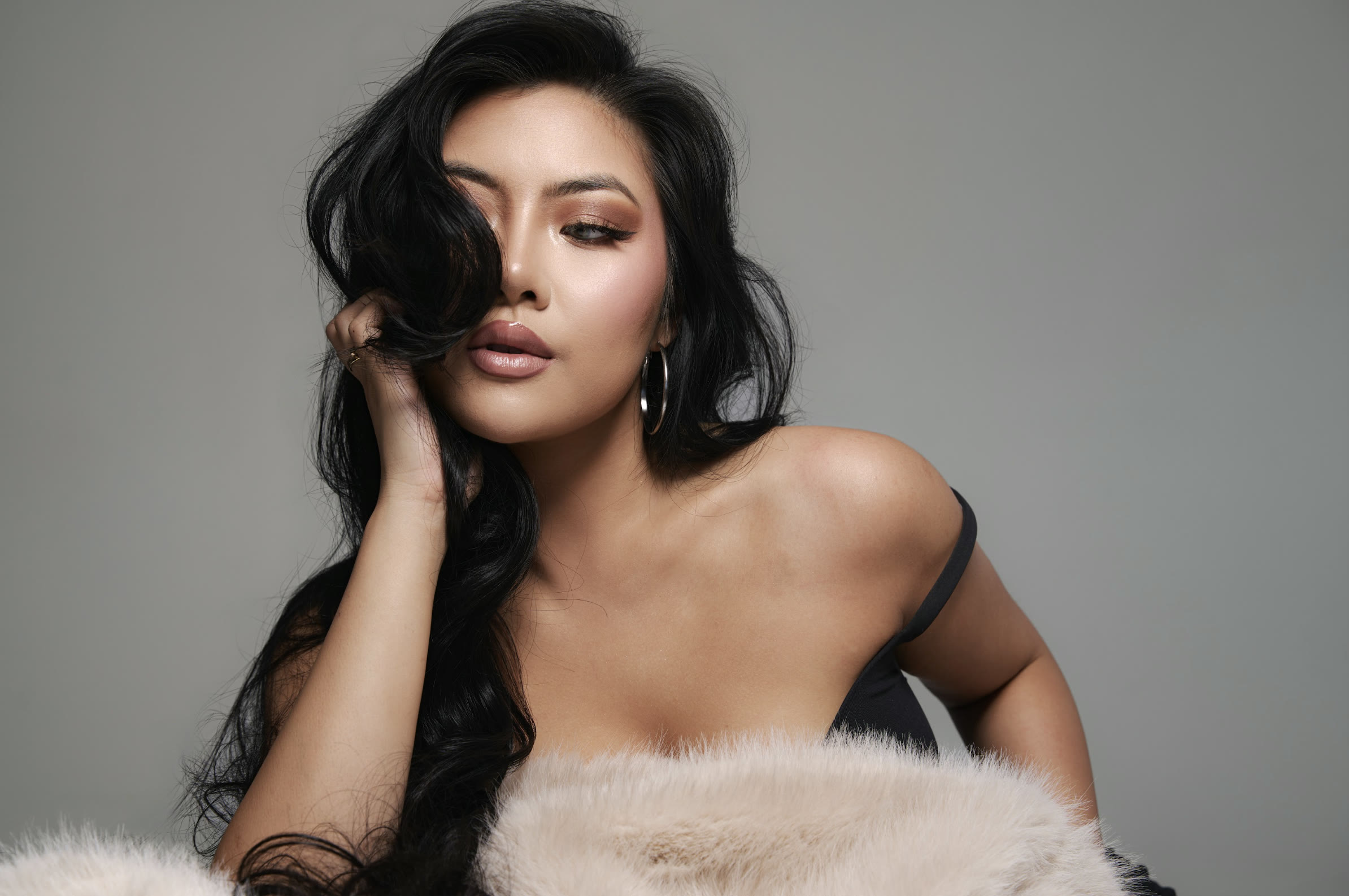 Vivian True in a fur coat with her hand in her hair, studio portrait