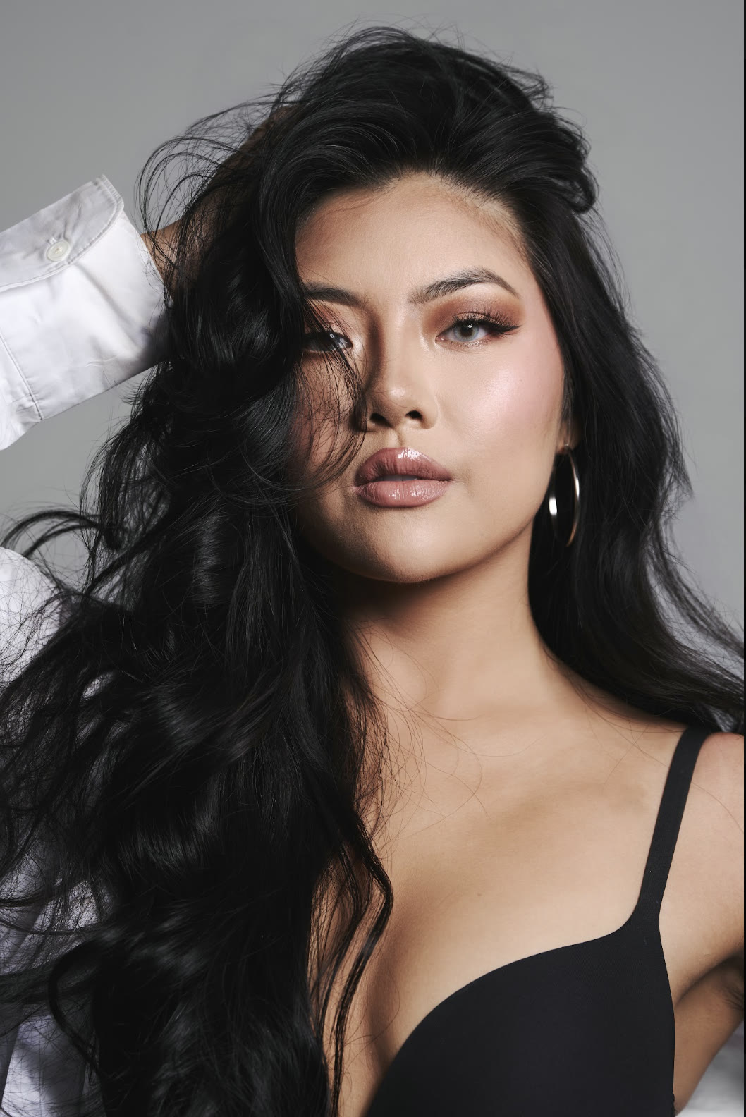 Vivian True with her hand in her hair in a black top, studio portrait